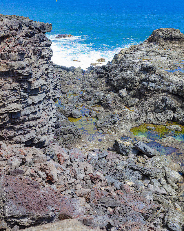 Les Trois-Bassins岩石海岸，La Reunion岛晴朗的一天与强烈的蓝色大海。